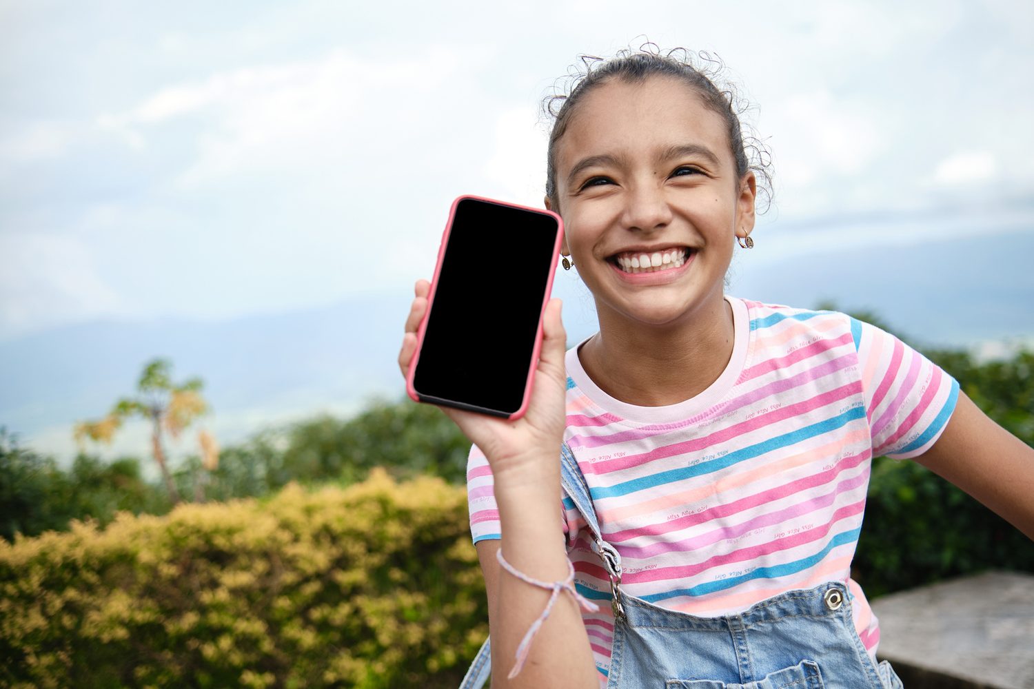 Une adolescente souriante montre son smartphone
